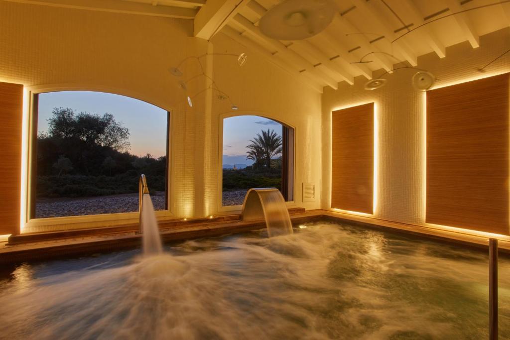 a hot tub with water in a room with windows at Fontsanta Hotel Thermal & Spa - Adults Only in Colònia de Sant Jordi
