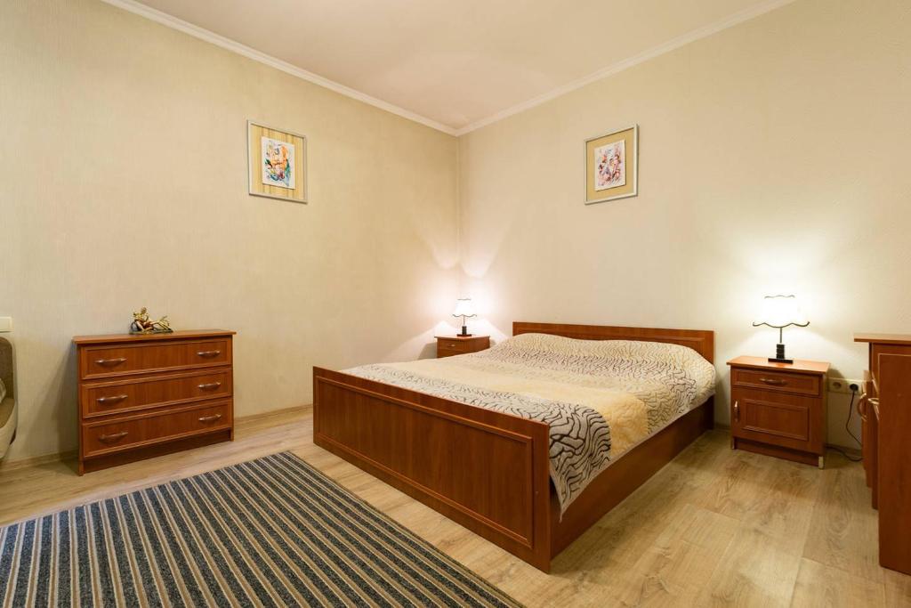 a bedroom with a bed and two dressers and two lamps at Nadezhda Apartment on Nauryzbay Batyra 37/1 in Almaty