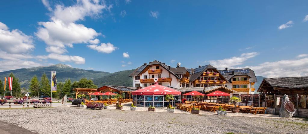 um resort com guarda-sóis vermelhos, mesas e edifícios em Grizzly Sport & Motorrad Resort em Sankt Margarethen im Lungau