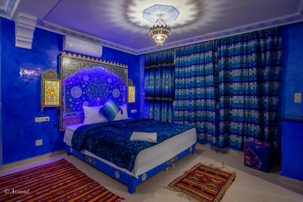 a blue bedroom with a bed and a chandelier at Puerta Azul in Chefchaouen