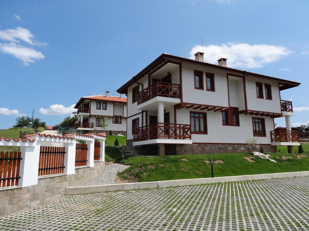 a large white house with a cobblestone street at Guest House Ivanini Houses in Tryavna
