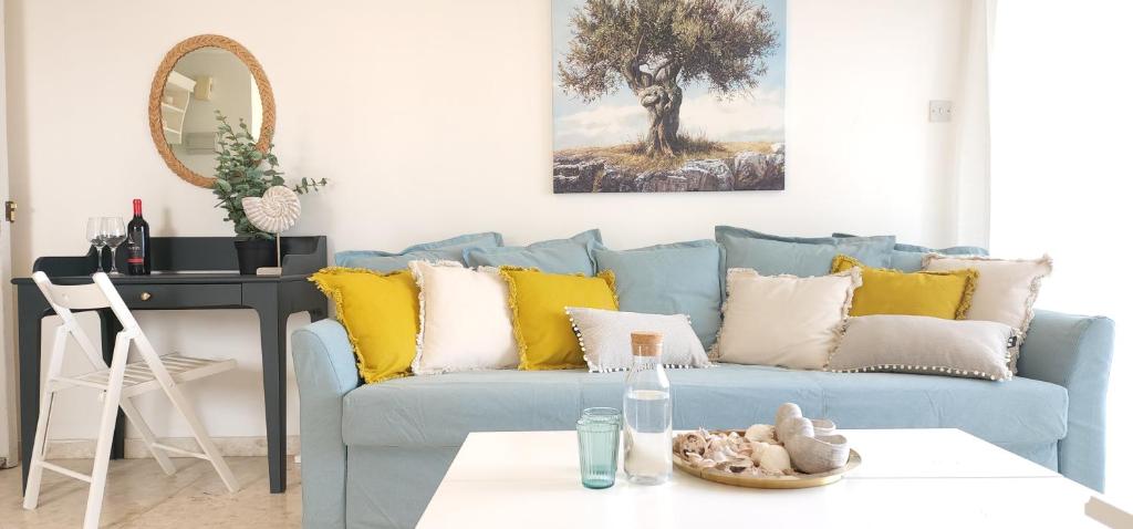 a living room with a blue couch with yellow pillows at Capri Sea View One Bedroom in Larnaka