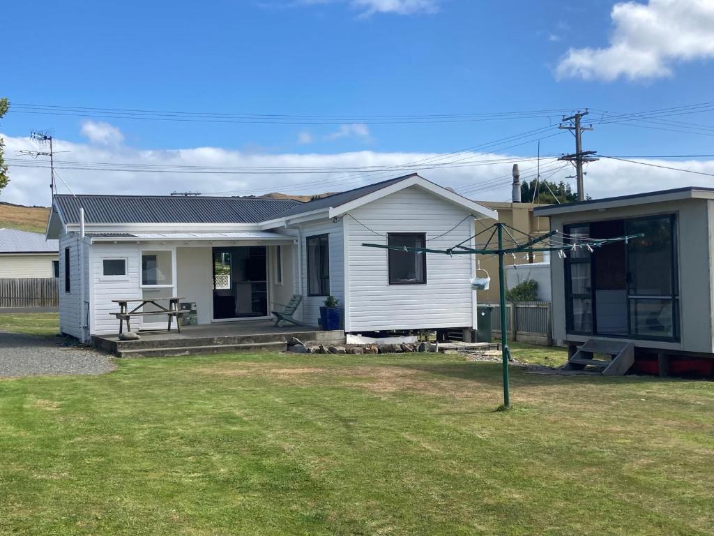 a small white house with a yard at Kiwi beach bach in Riverton