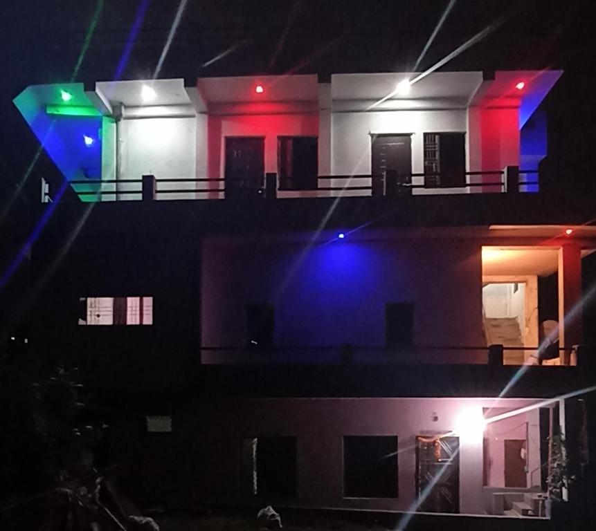 un edificio con luces rojas azules y verdes. en SHREE HOME STAY en Dwārāhāt