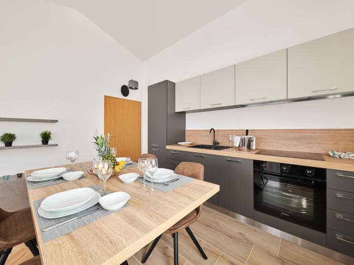 a kitchen with a wooden table with plates and wine glasses at Ribarska Koliba - Villa Marija in Pula