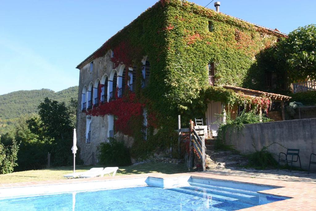 a building with a swimming pool next to a house at Casa Rural Mas Garganta in La Pinya