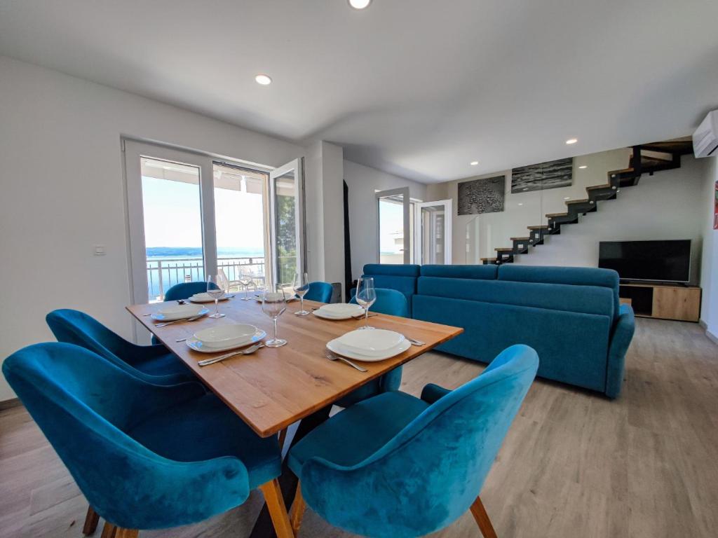 a dining room with a table and blue chairs at villa MIJO in Brela