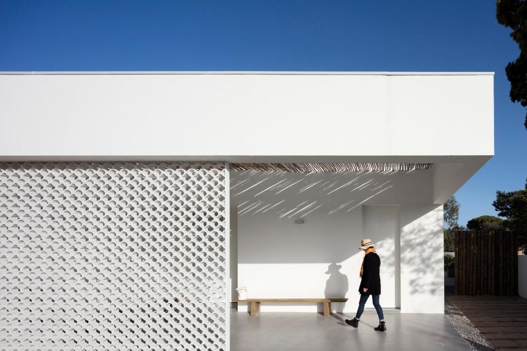 a man walking past a bench in front of a building at Precious House in Comporta in Carvalhal