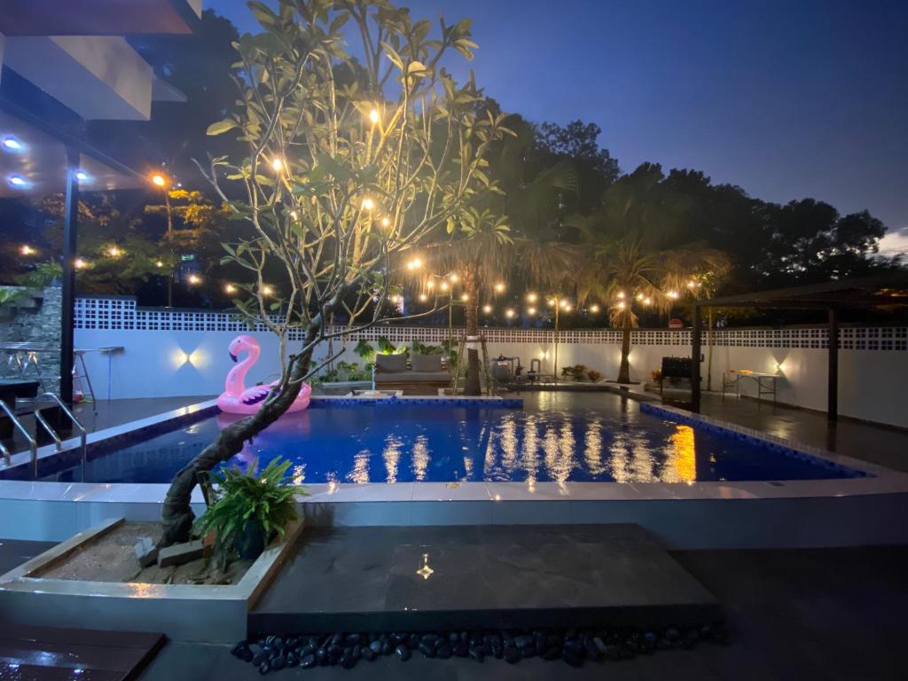 DE' IMPIIANA VILLA Johor 1st Waterfalls Villa No Party and Event في جوهور باهرو: شجرة فلامنغو وردية في حمام السباحة في الليل