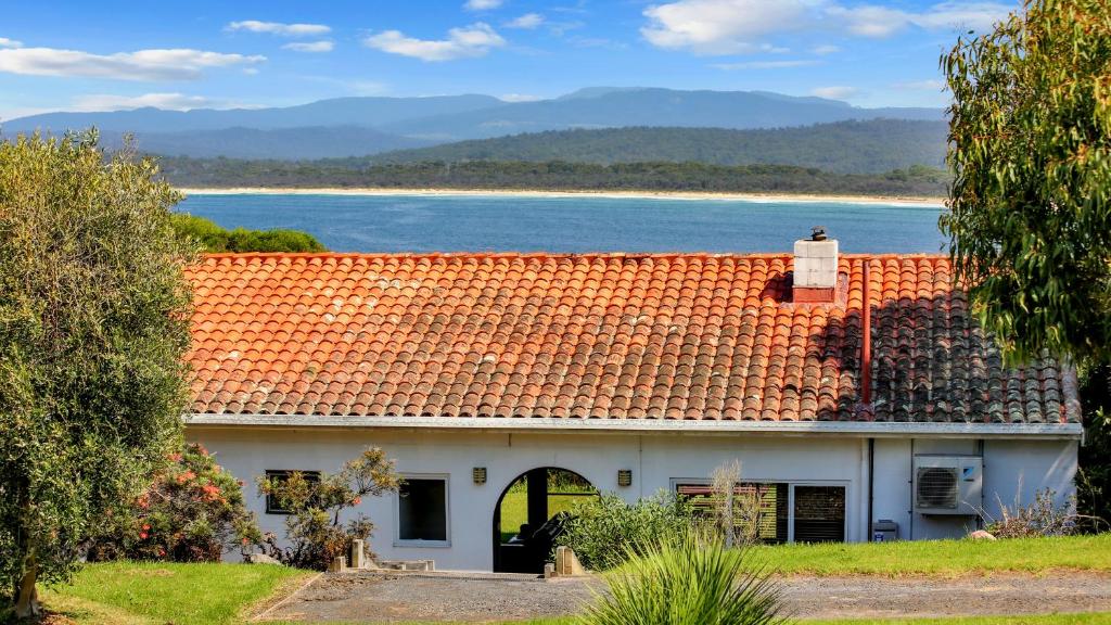 une maison avec un toit orange et une vue sur l'océan dans l'établissement Cordova - Perfect Summer or Winter Getaway, à Merimbula