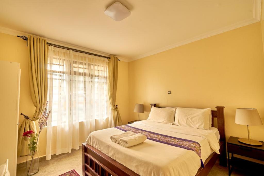 a bedroom with a large bed and a window at The Cottage Residence Karen in Nairobi