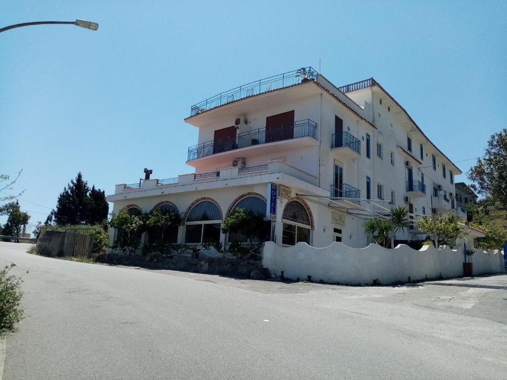 ein großes weißes Gebäude an der Straßenseite in der Unterkunft Hotel Conca d'Oro in Stalettì