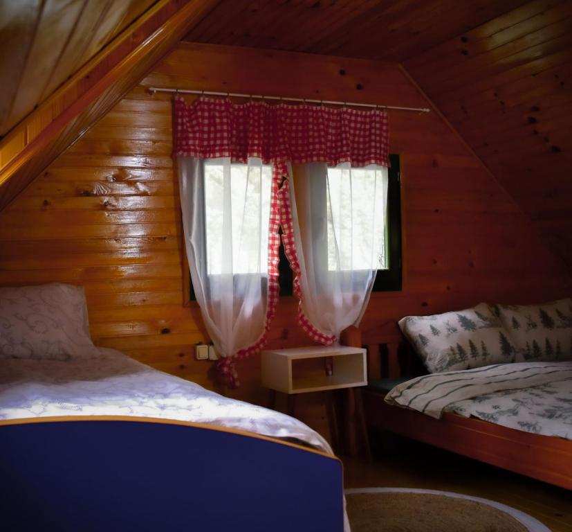 a bedroom with two beds in a log cabin at Vikendica,, Tadic,, Ovčar Banja in Ovčar Banja