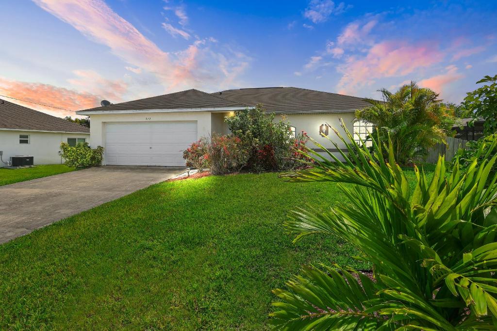 a house with a yard with a garage at Family vacation, heated pool, wake up to enjoy the sunrise - Villa Pine Island in Cape Coral