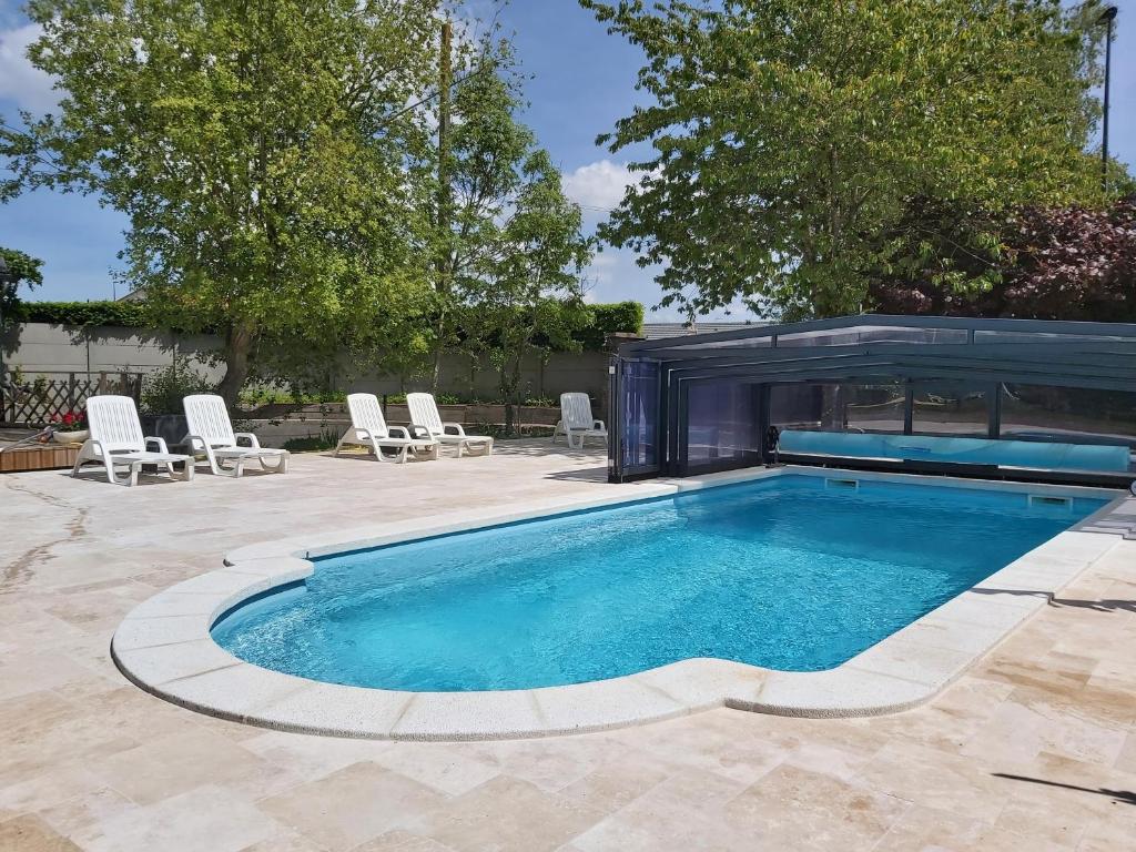 a swimming pool in a backyard with chairs and a building at Le R'Epi Normand Chambres d'hôtes et Spa in Ourville-en-Caux