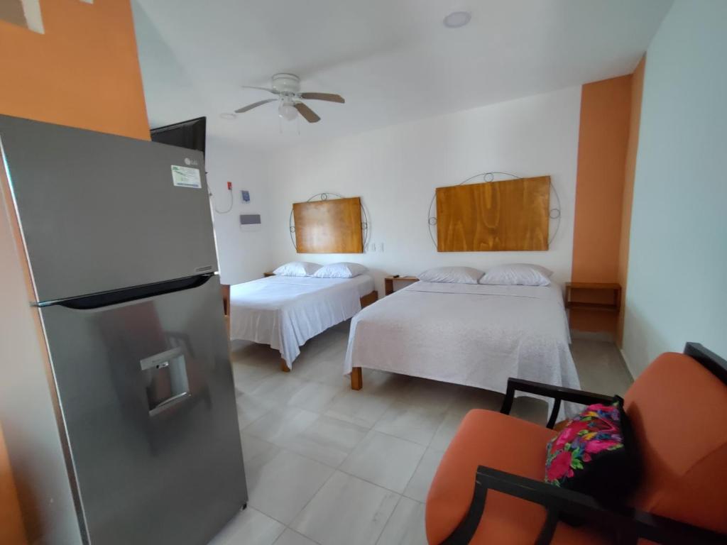 um quarto com 2 camas e um frigorífico em Buenosdías Izamal em Izamal