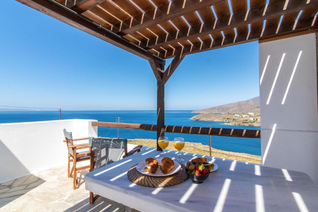 a table with a plate of food on a balcony with the ocean at Sail Inn in Agios Romanos