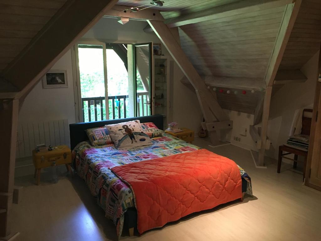 Schlafzimmer mit einem Bett mit einer roten Bettdecke in der Unterkunft Chambre avec balcon et salle de bains privée in Bouloire