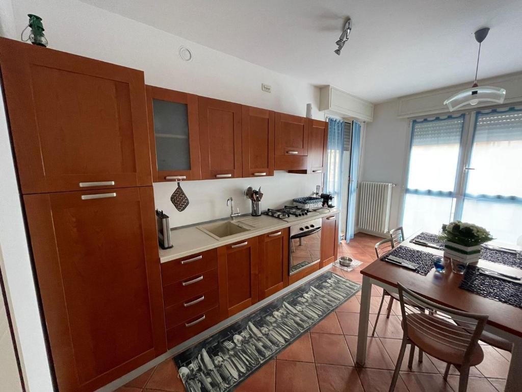 cocina con armarios de madera, mesa y comedor en B.d.B Apartment, en Cattolica