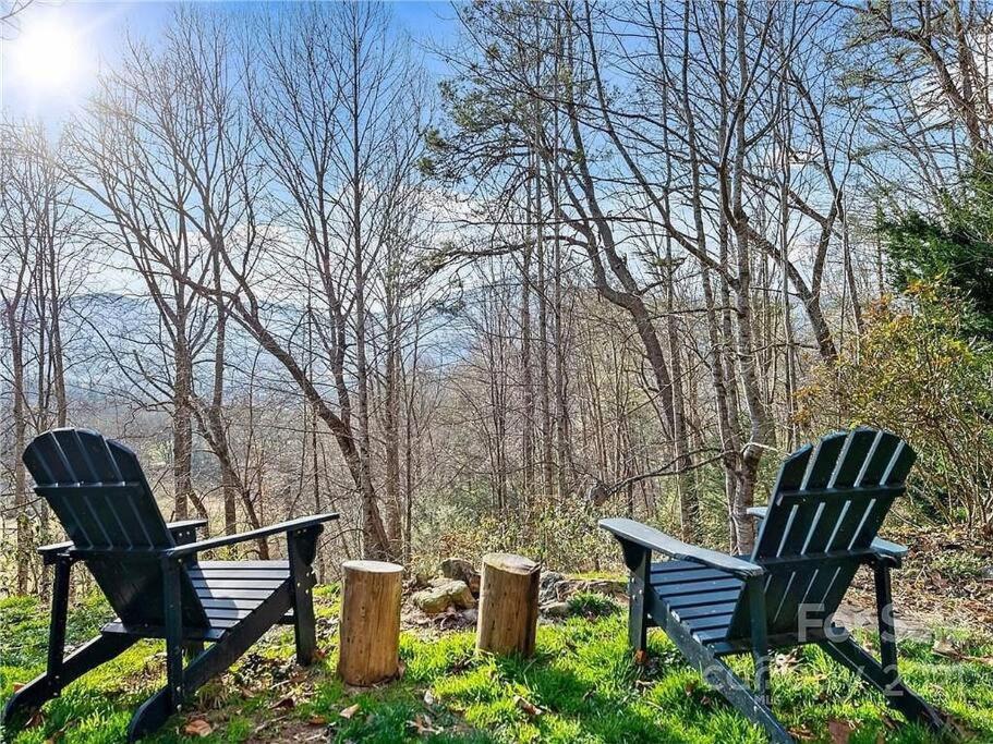 dos sillas sentadas en el césped junto a los árboles en Misty Mountain Cottage, en Waynesville