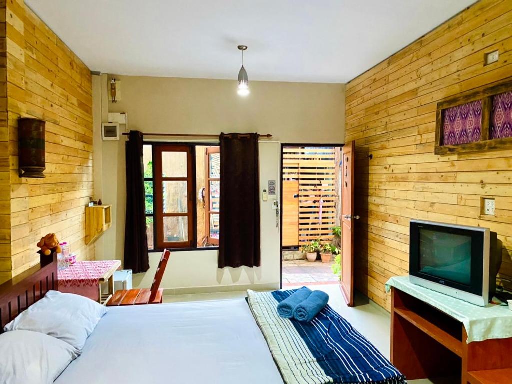 um quarto com uma cama e uma televisão num quarto em Thai Guesthouse em Kanchanaburi