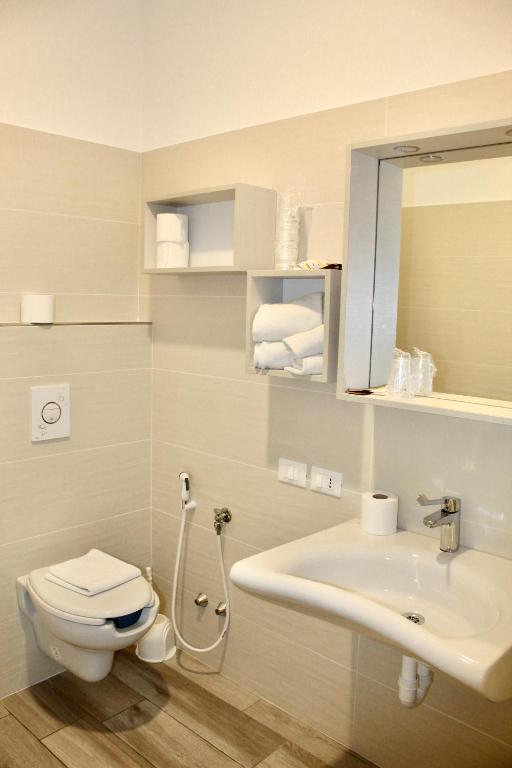 łazienka z toaletą, umywalką i lustrem w obiekcie Hotel Cristina w Grado