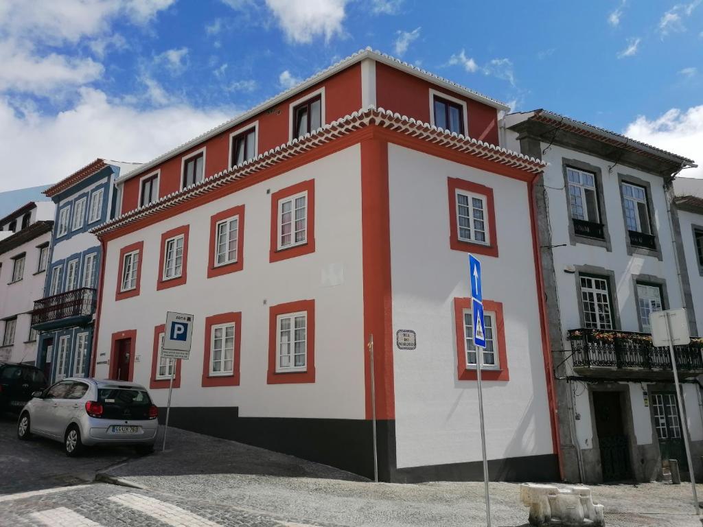 ein rot-weißes Gebäude mit einem Auto, das vorne geparkt ist in der Unterkunft Miragaia Star Apartments in Angra do Heroísmo
