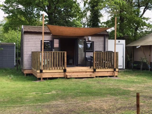 ein kleines Haus mit einer Veranda und einer Terrasse in der Unterkunft Tiny House de Wood Lodge in Ootmarsum