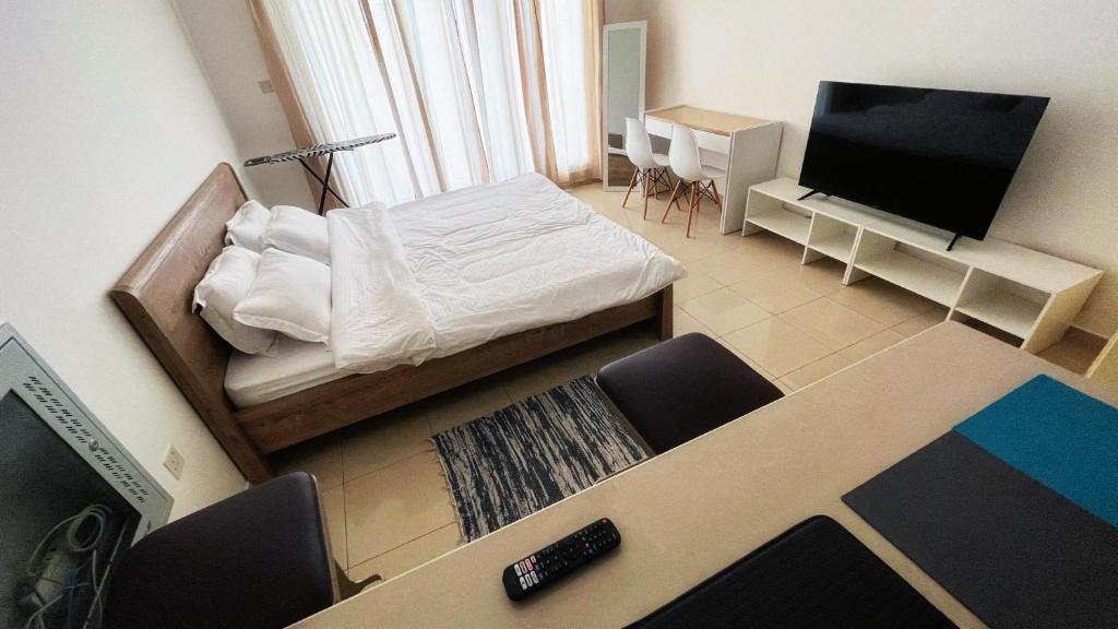 ein kleines Schlafzimmer mit einem Bett und einem Flachbild-TV in der Unterkunft Cozy Studio On The Beach in Ras al Khaimah