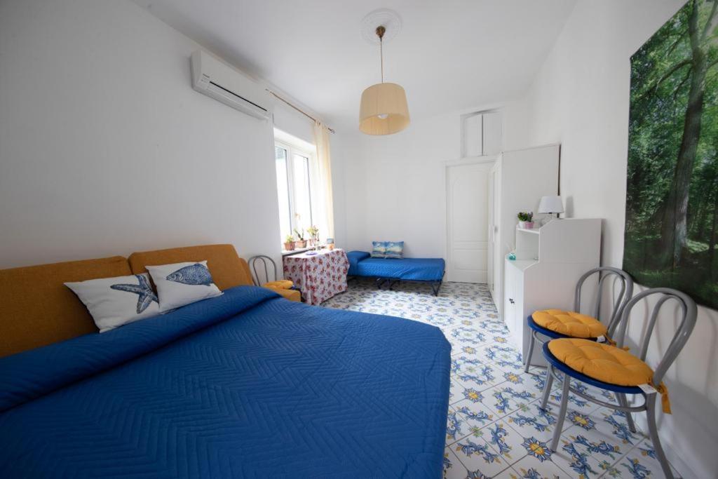 a bedroom with a blue bed with two chairs and a refrigerator at La Preferita del Doge in Atrani