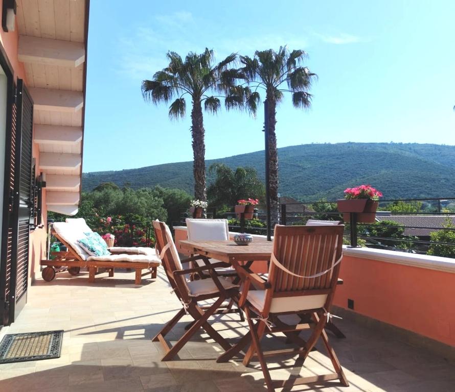een patio met een tafel, 2 stoelen en palmbomen bij Una fuga inaspettata in Castellabate