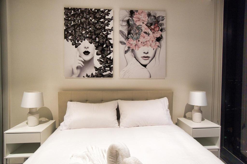 ein Schlafzimmer mit einem Bett mit zwei Bildern an der Wand in der Unterkunft Queen Bed Luxury Parisian Paradise with Amazing City Views, Spa, Gym, Steam & Sauna Rooms in Adelaide