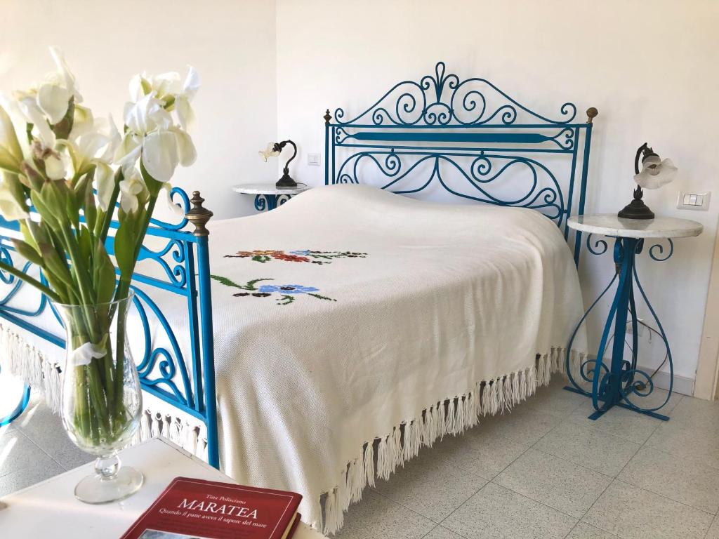 a blue bed with a vase of flowers on a table at Relax Maratea in Maratea