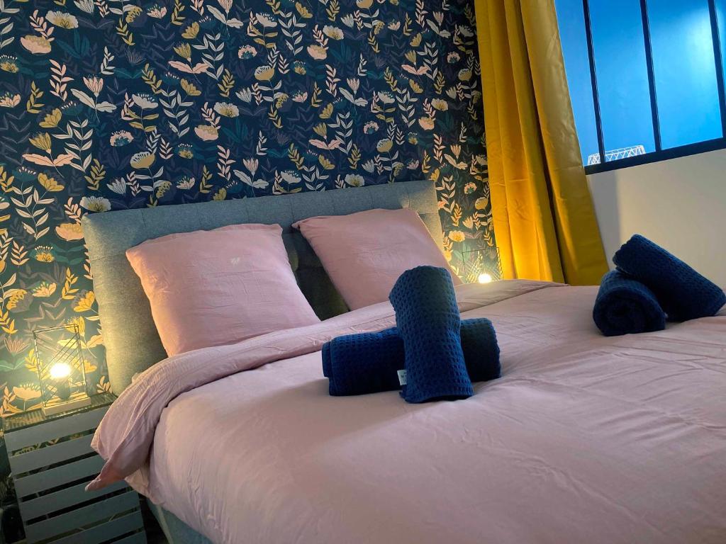 Una cama con almohadas rosas y toallas azules. en La Rochelle Gabut Vieux Port superbe emplacement, en La Rochelle
