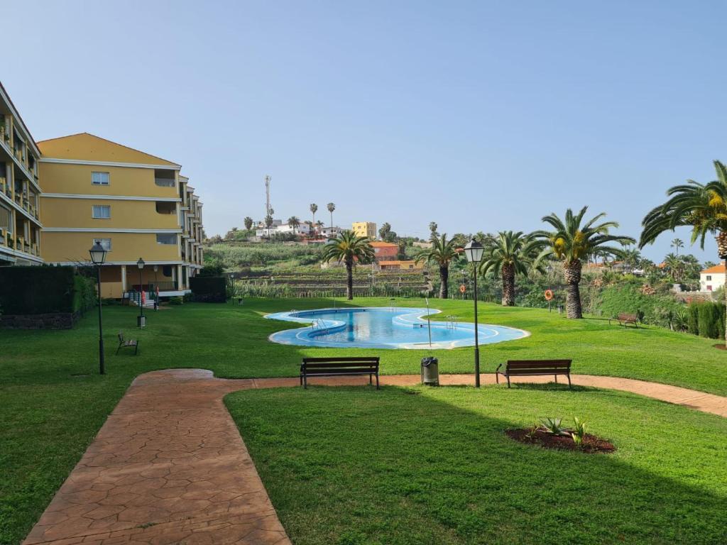 een park met twee banken en een zwembad bij La Quinta Relax in Santa Úrsula