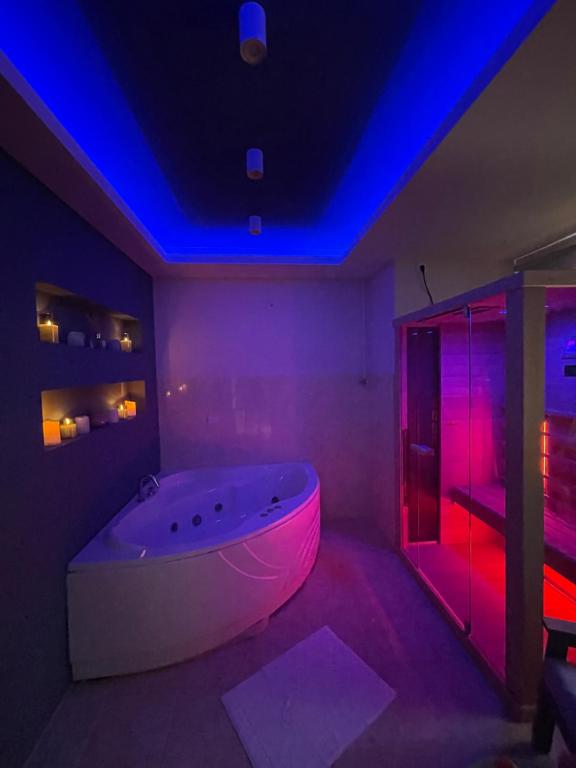 una vasca bianca in una stanza con luci viola di Apartman Spa Bačka a Bačka Palanka