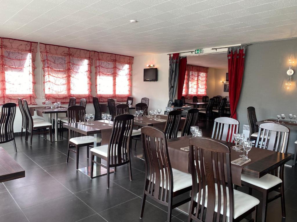 a dining room with tables and chairs and windows at Citotel Hôtel Le Capricorne in Marmande