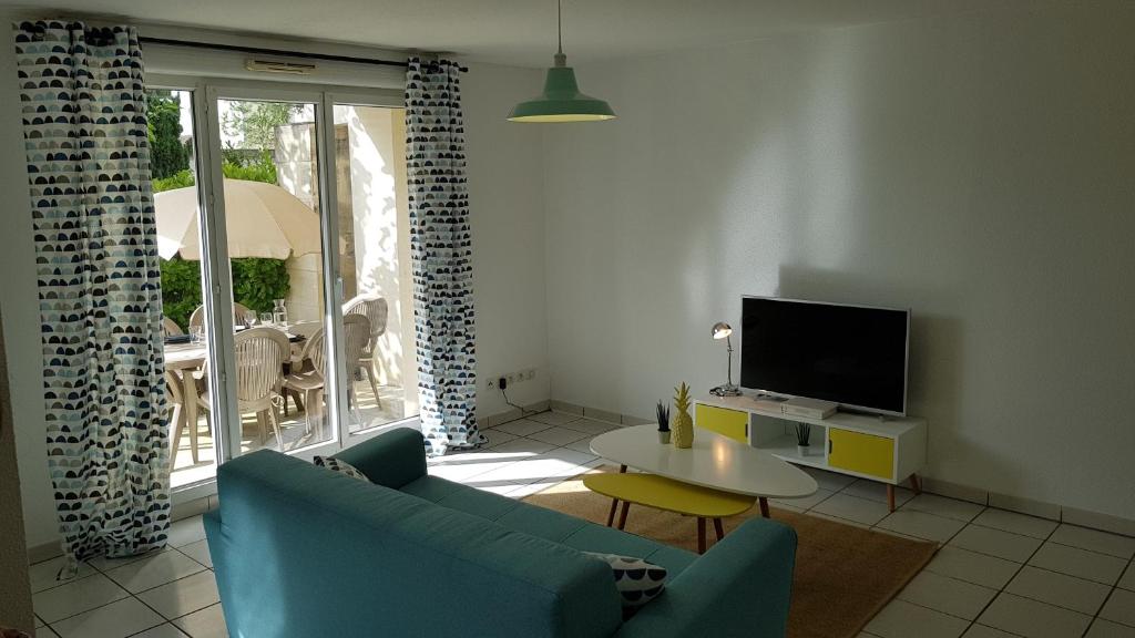 a living room with a blue couch and a tv at Appartement 2 pièces avec jardin privatif in Saint-André-de-Cubzac