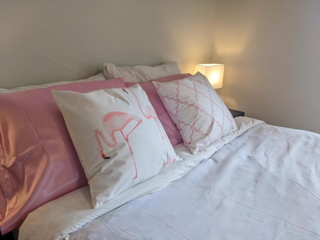 Una cama con almohadas rosas y blancas. en Pink Flamingo, en Wolfville