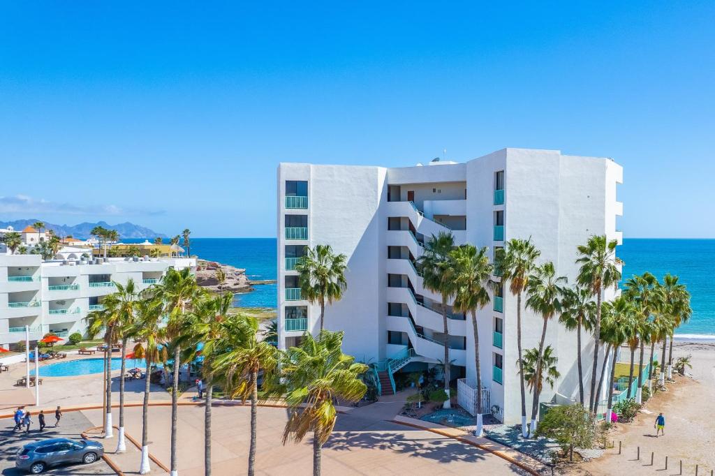 サン・カルロスにあるCondominios San Carlosのホテルとヤシの木が茂るビーチの景色を望めます。