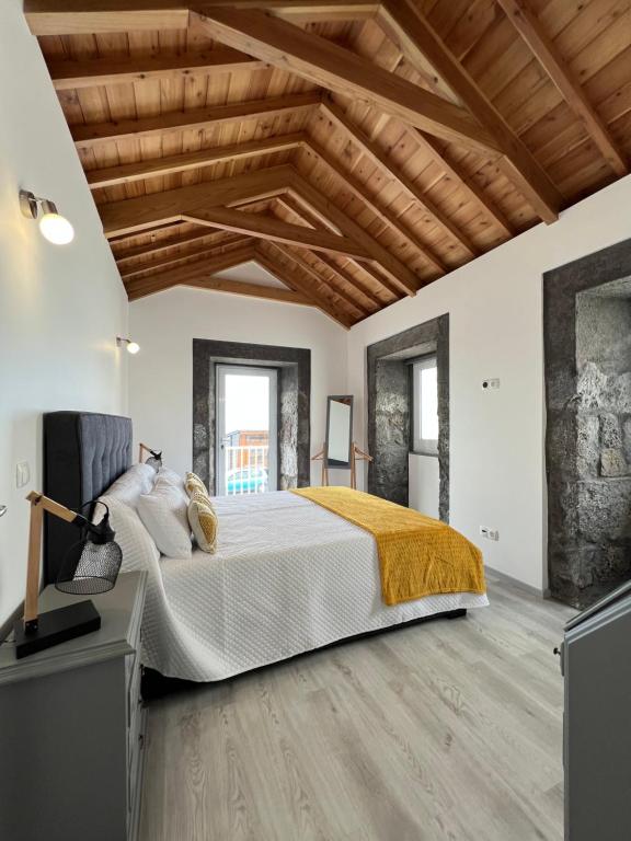 a bedroom with a large bed and wooden ceilings at Casa do Craveiro in Lajes do Pico
