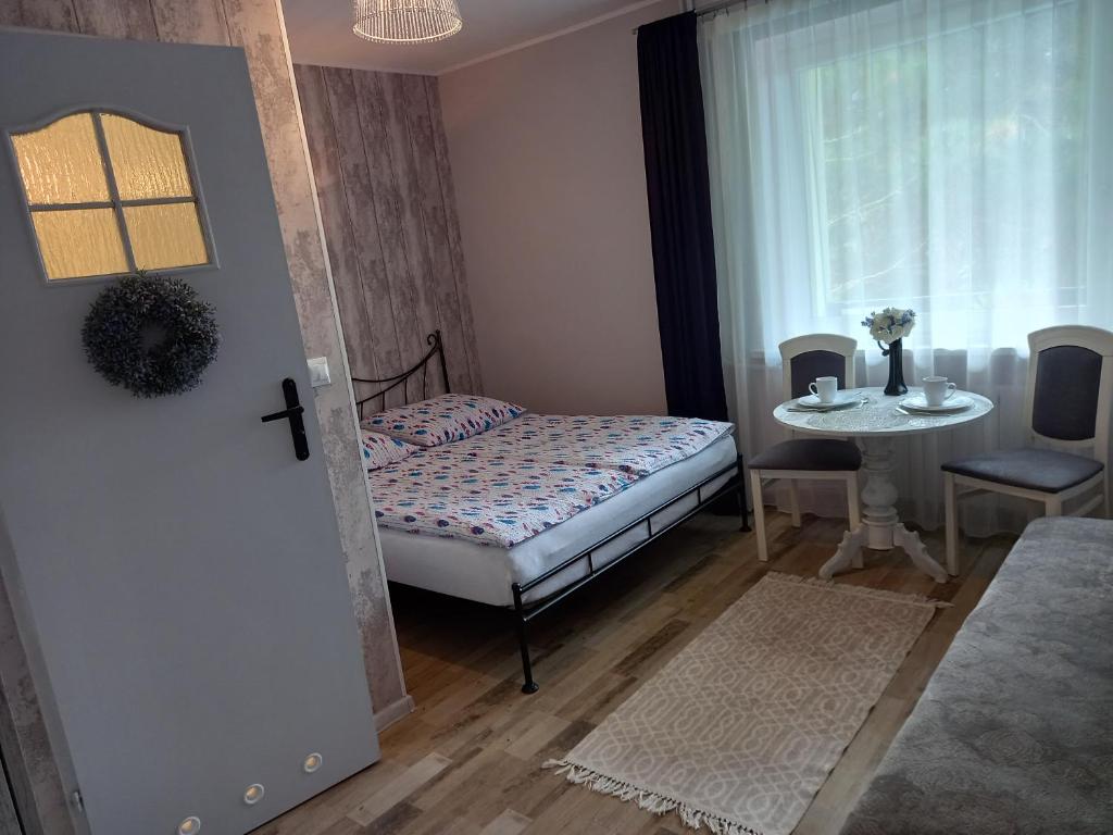 a bedroom with a bed and a table and a window at Villa Jaskółka in Międzyzdroje