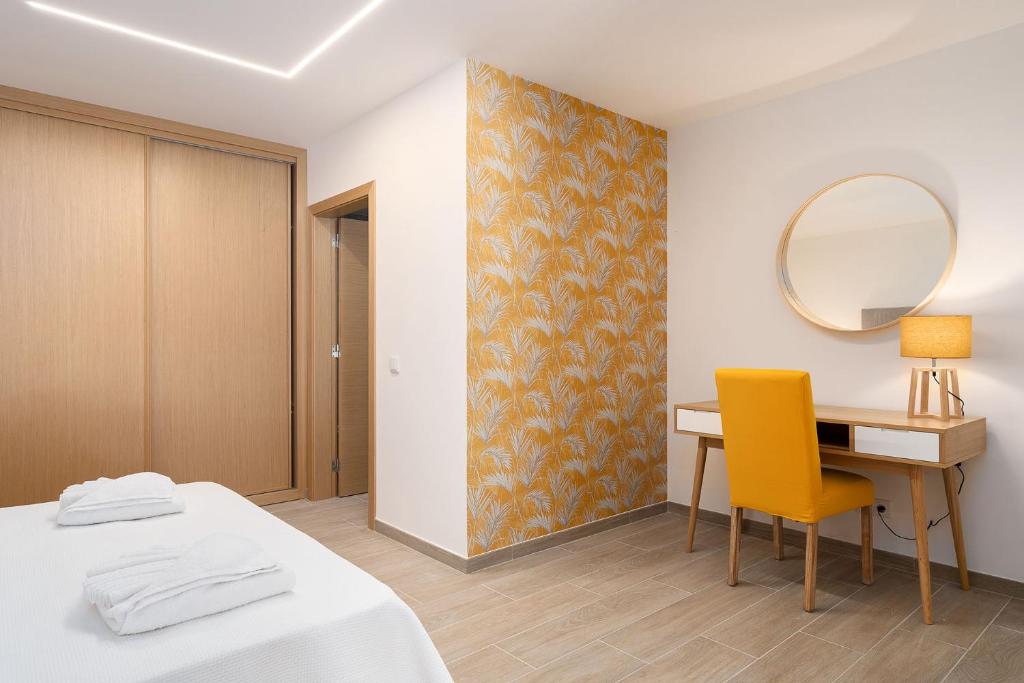 a bedroom with a bed and a desk and a mirror at Quinta das Andorinhas in Carvoeiro