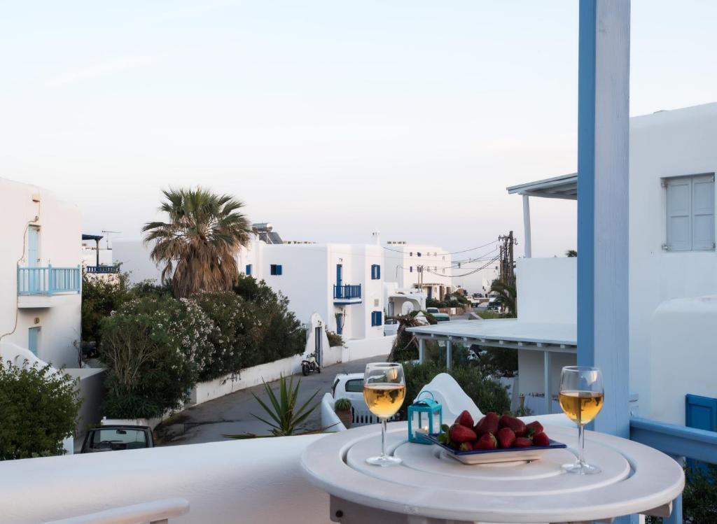 a table with two glasses of wine and a plate of fruit at Escape to Mykonos - Entire place by Ornos beach in Ornos