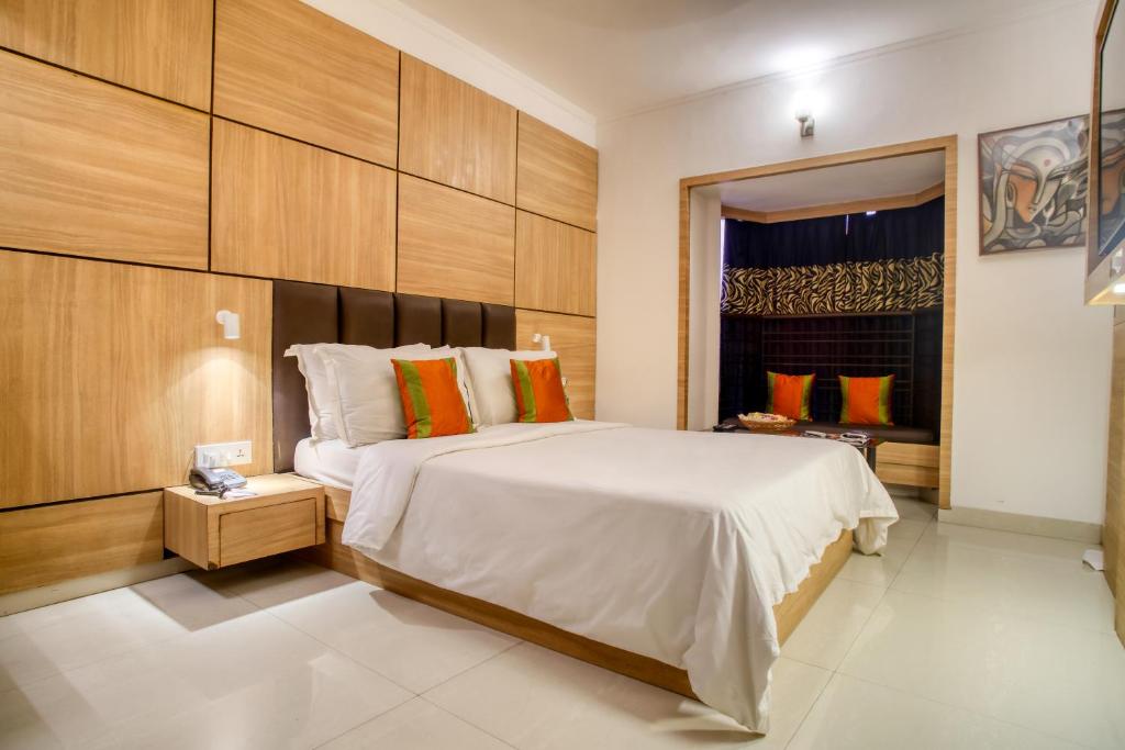 um quarto com uma grande cama branca e uma janela em Roland Hotel em Calcutá