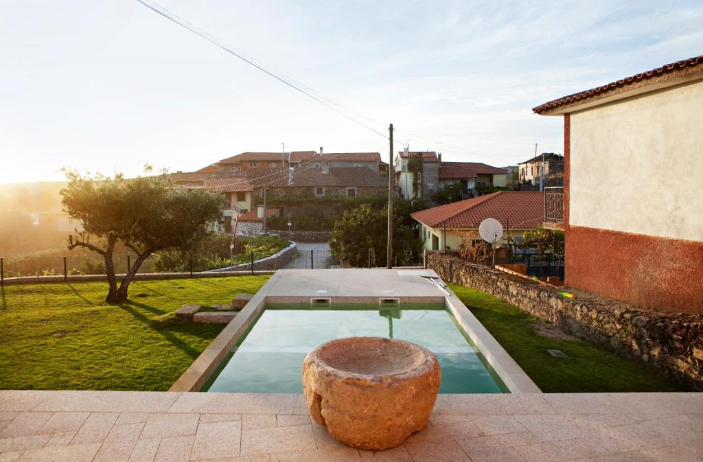 a pool with a rock sitting on the edge of a house at Casas de Vale de Lobo in Mirandela