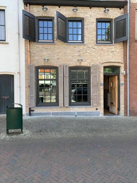 een bakstenen gebouw met ramen en een vuilnisbak voor de deur bij Toplocatie in centrum Sluis in Sluis