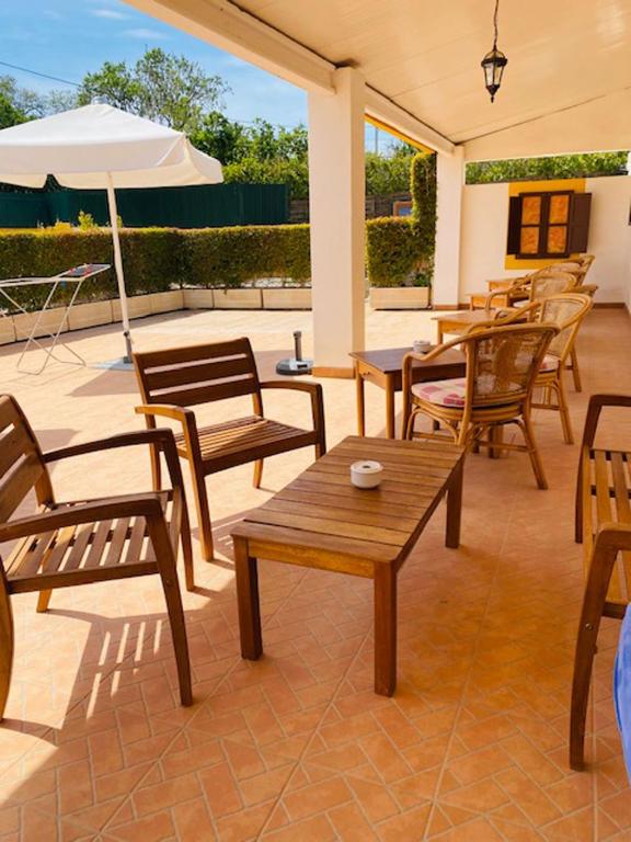 a patio with wooden chairs and tables and an umbrella at Quinta das Andorinhas in Carvoeiro