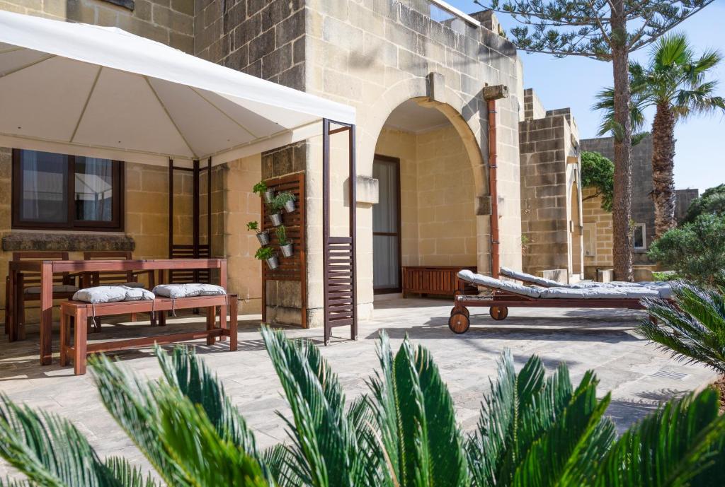 a patio with two beds and an umbrella at Luzzu - Family Friendly Maisonette in Xlendi