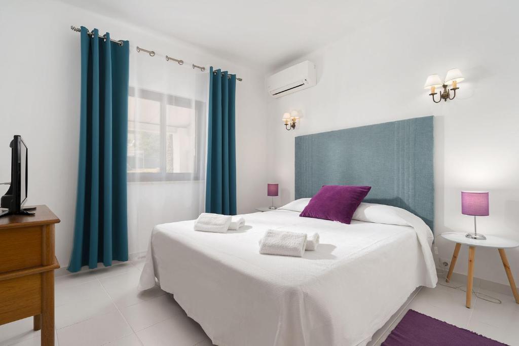 a bedroom with a large white bed with purple accents at Quinta das Andorinhas in Carvoeiro